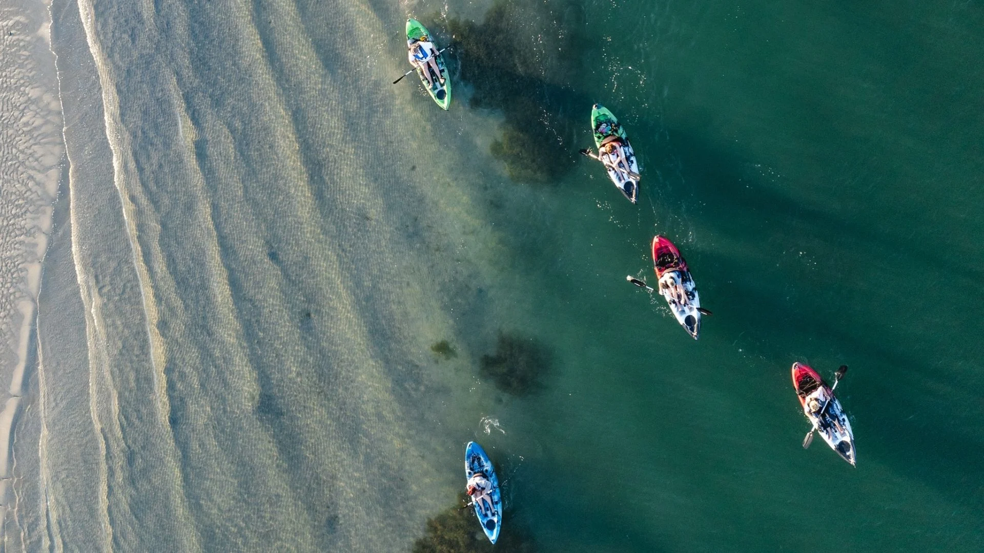 Top-down aerial view of kayakers paddling through the Mandurah Estuary.
