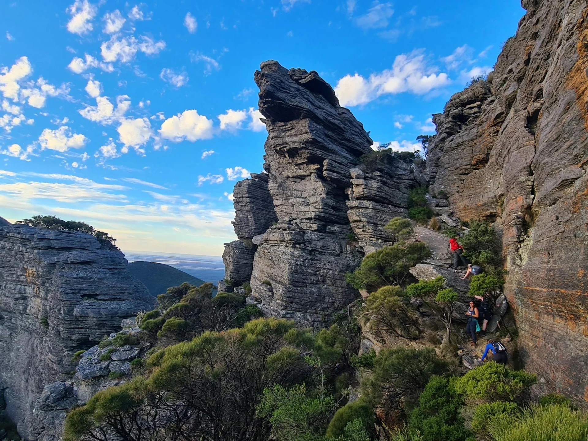 Giant mountain peak with hikers scaling the rock face