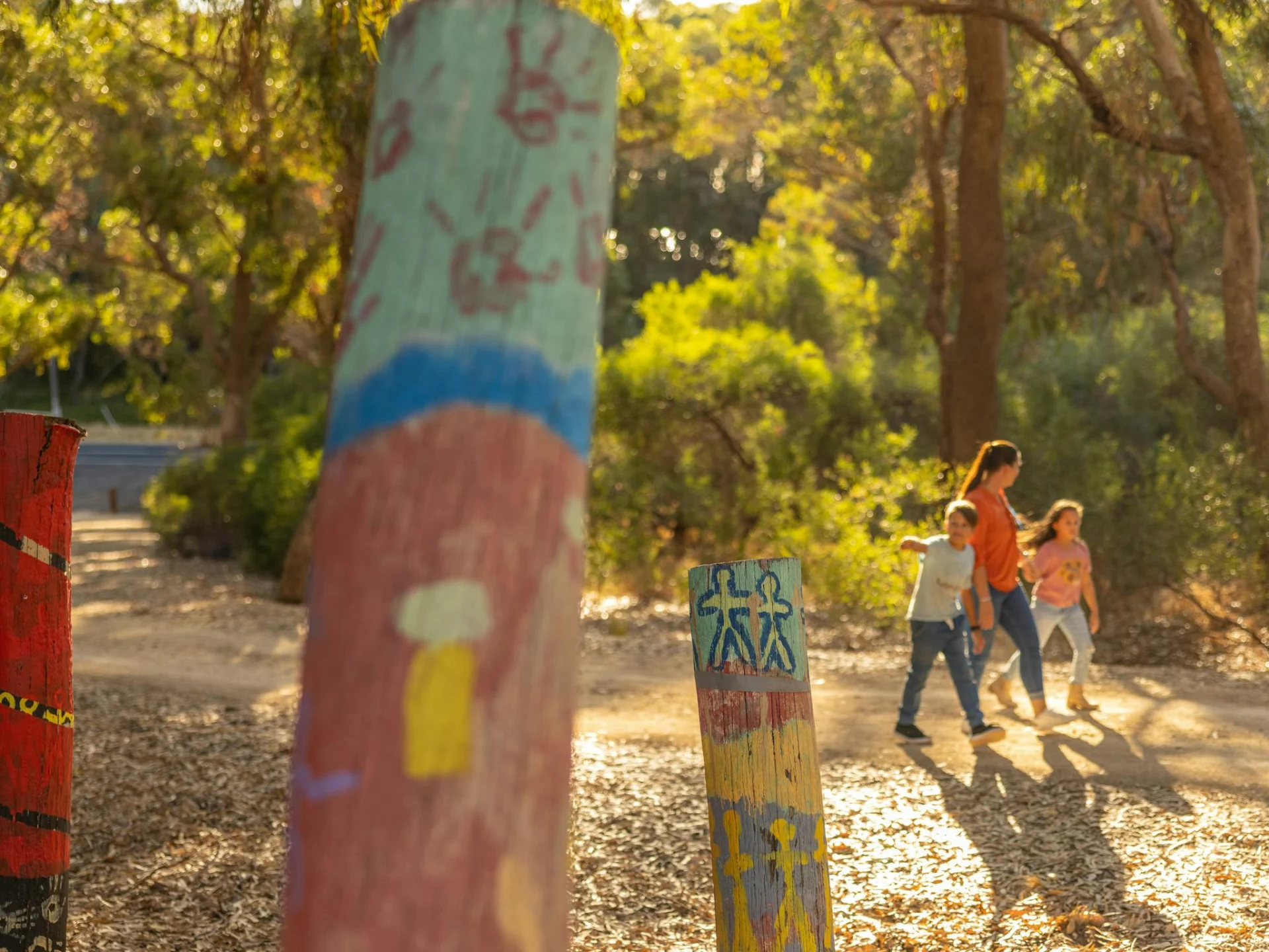 Mother and two children strolling along the nature path with three painted posts in the frontage.