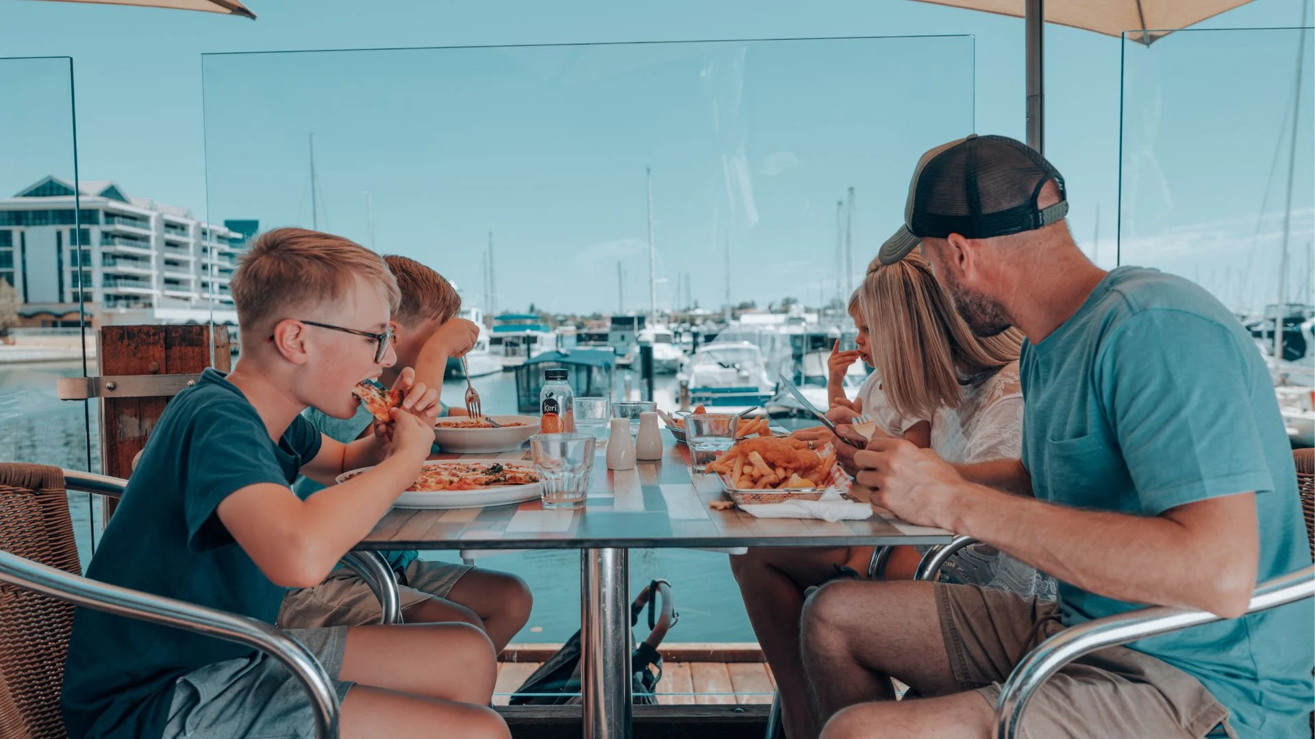 A family with three young boys enjoying a meal at Sharky's Mandurah, overlooking the Mandurah Ocean Marina.