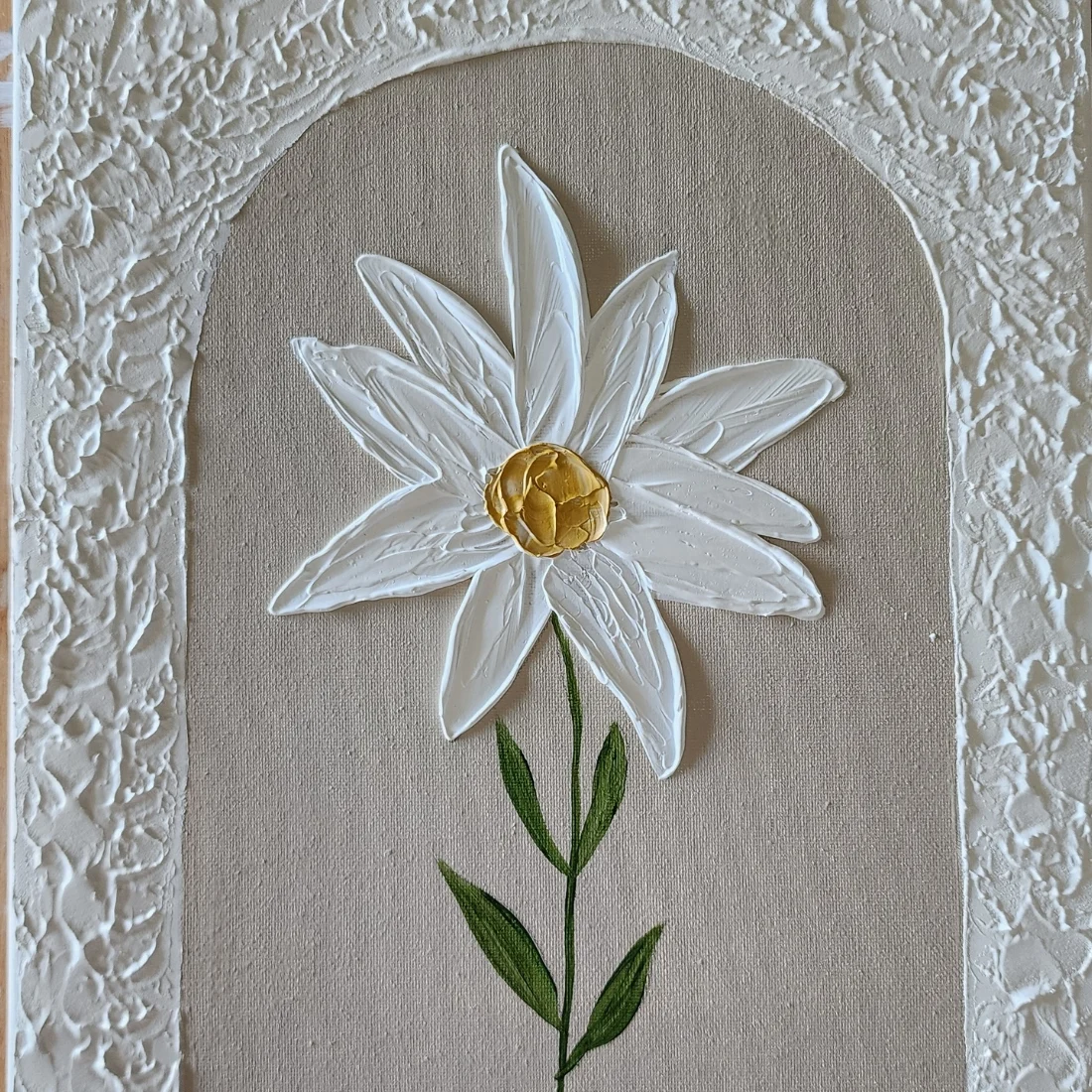 A textured painting of a white daisy with a yellow center and green stem, set against a tan background with a white, arched, and raised textured border.