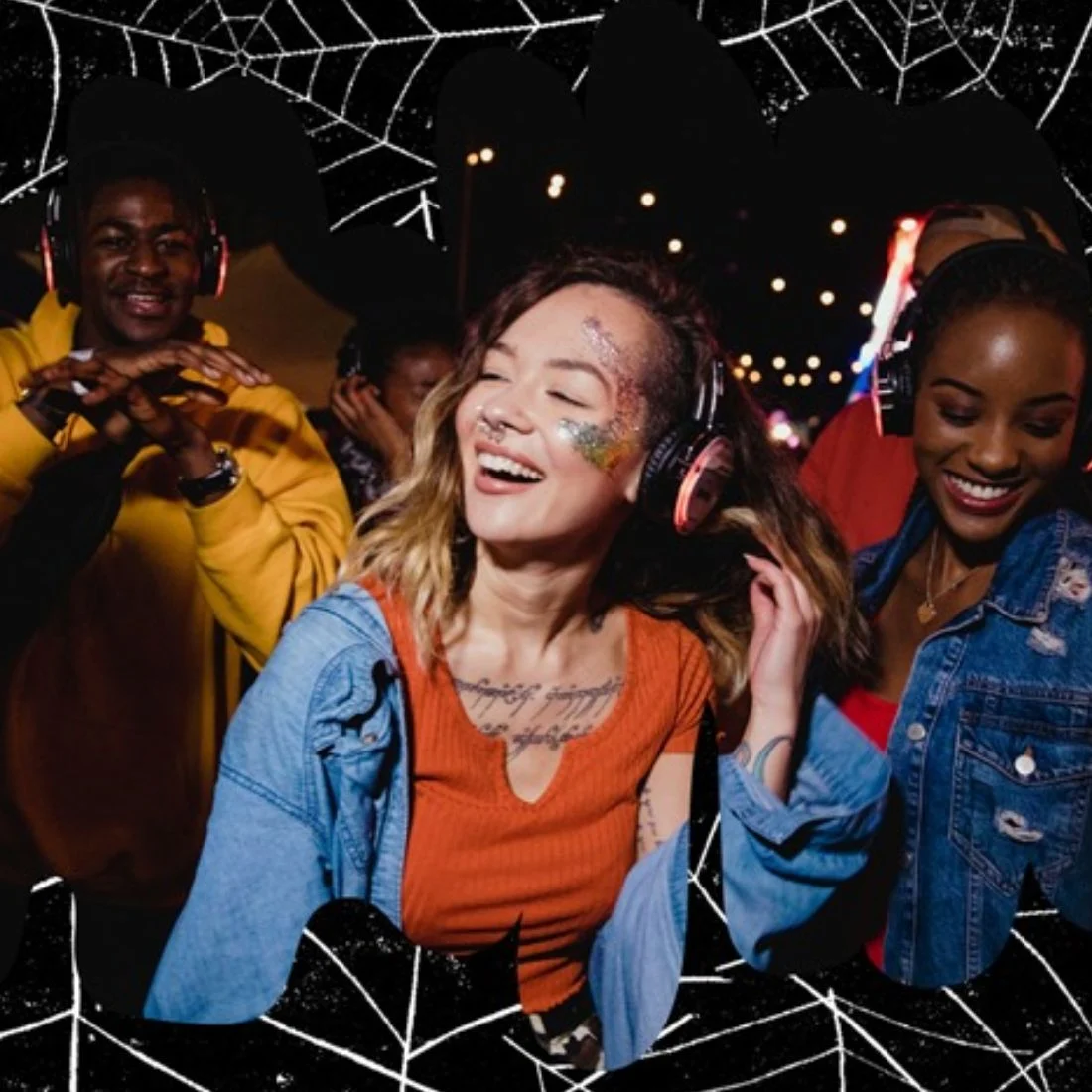 Two women and a man smiling and dancing while wearing headphones at a night event, with colorful lights illuminating their faces.