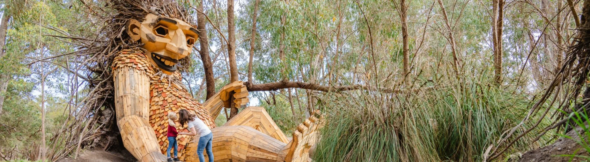 Mother and Daughter marveling at a large wooden sculputre among the bush