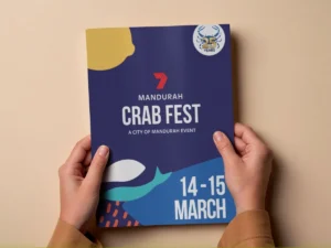 A person holds a colourful flyer for Mandurah Crab Fest, A City of Mandurah Event, taking place on March 14-15. The flyer features abstract sea-themed shapes and a 25 years badge in the top right corner.