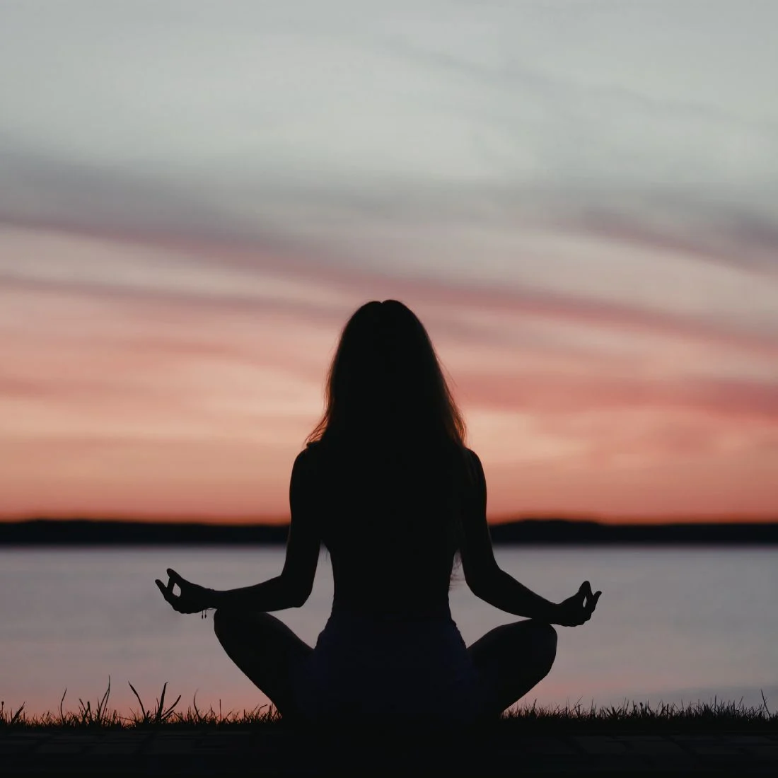 Silhouette of a woman meditating by the Mandurah Estuary at sunrise.