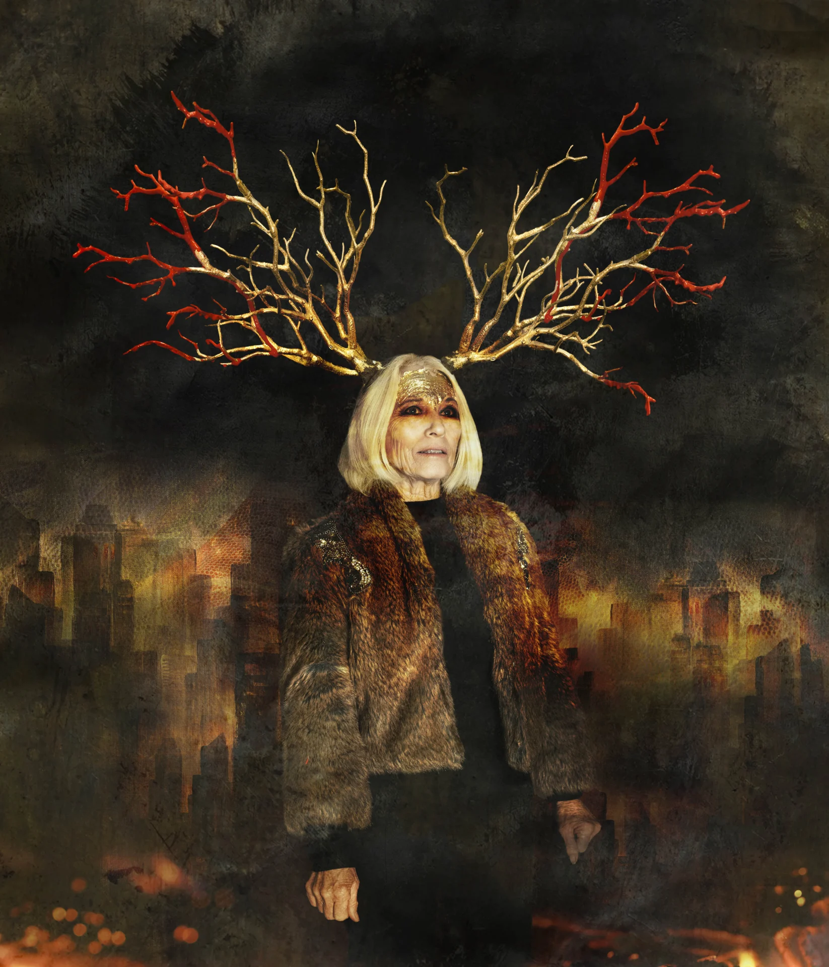 An older woman with white hair, wearing a fur coat, stands against a dark cityscape background. Large antlers made of red and gold branches extend from her head, blending with the fiery tones around her.