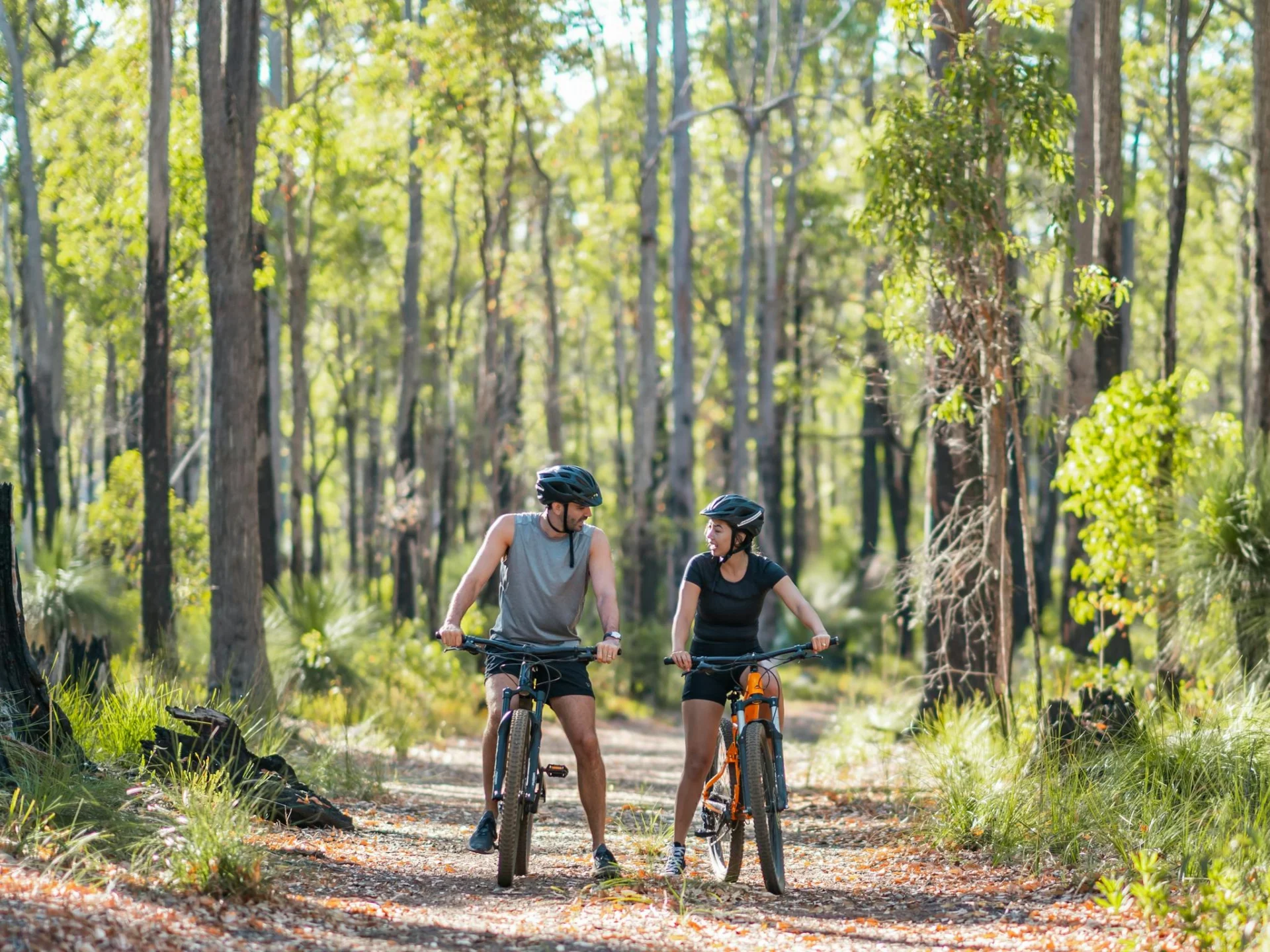 A male and female in activewear on mountain bikes on a forest trail in Dwellingup, Western Australi