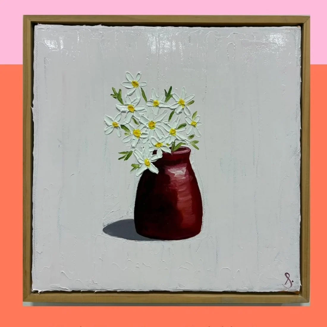A painting of white daisies with yellow centers in a dark red vase, set against a textured pale background. The artwork is framed and signed in the bottom right corner with an S.