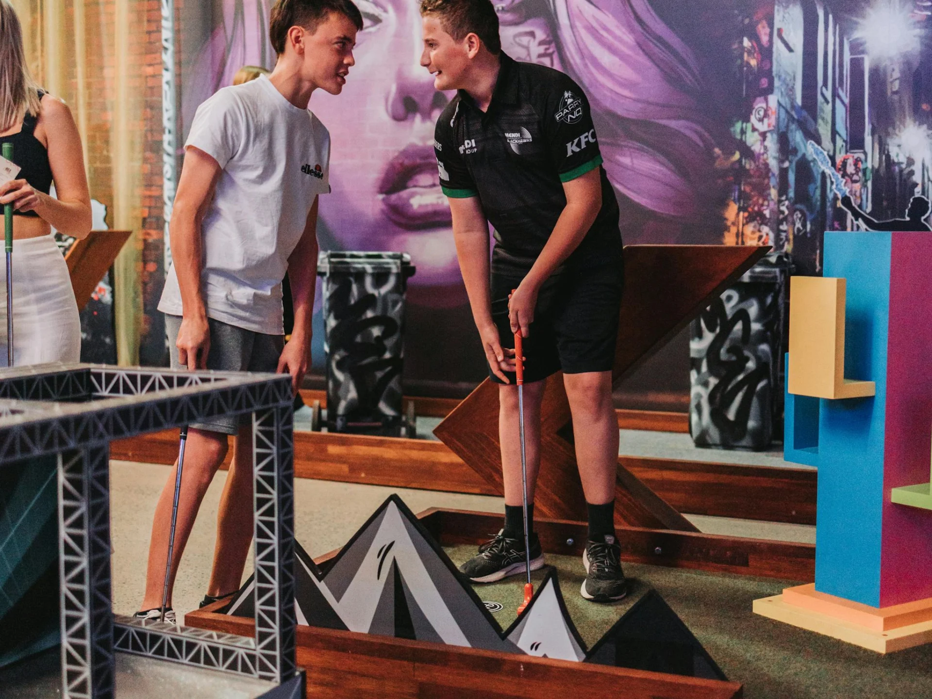 Two Men Playing Indoor Mini Golf at Hey Caddy Venue