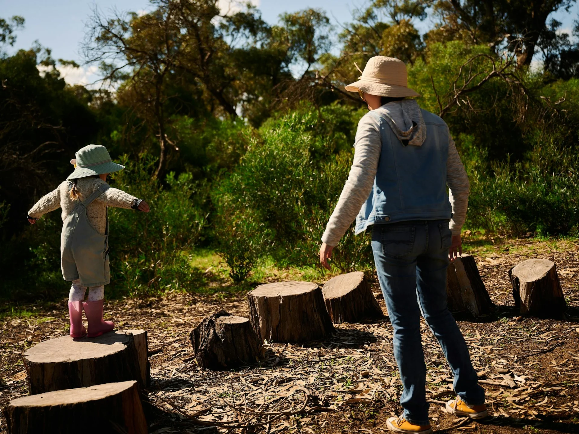 Child hopping across tree stumps