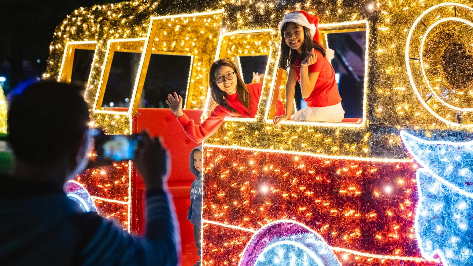 Visitors pose in a glowing Christmas train light display during festive celebrations in Mandurah.