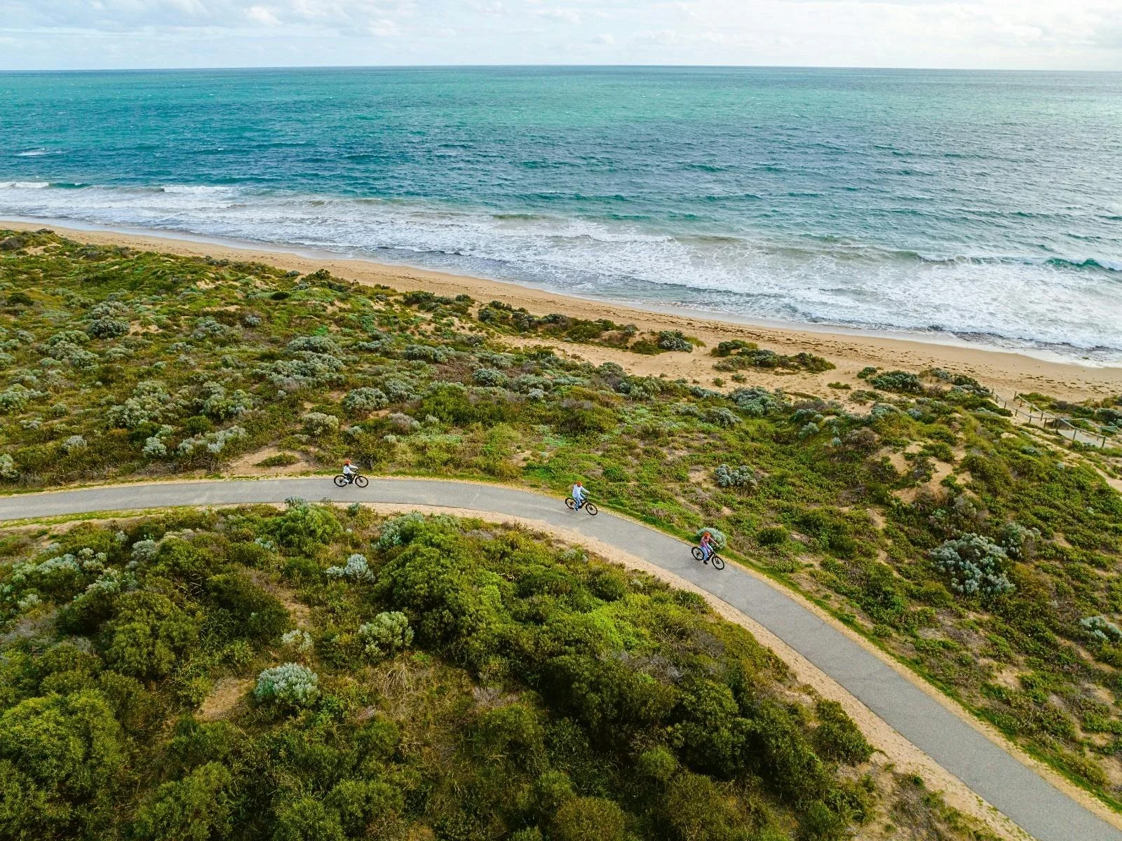 Cyclists ride along the Halls Head coastal path beside the Indian Ocean in Mandurah