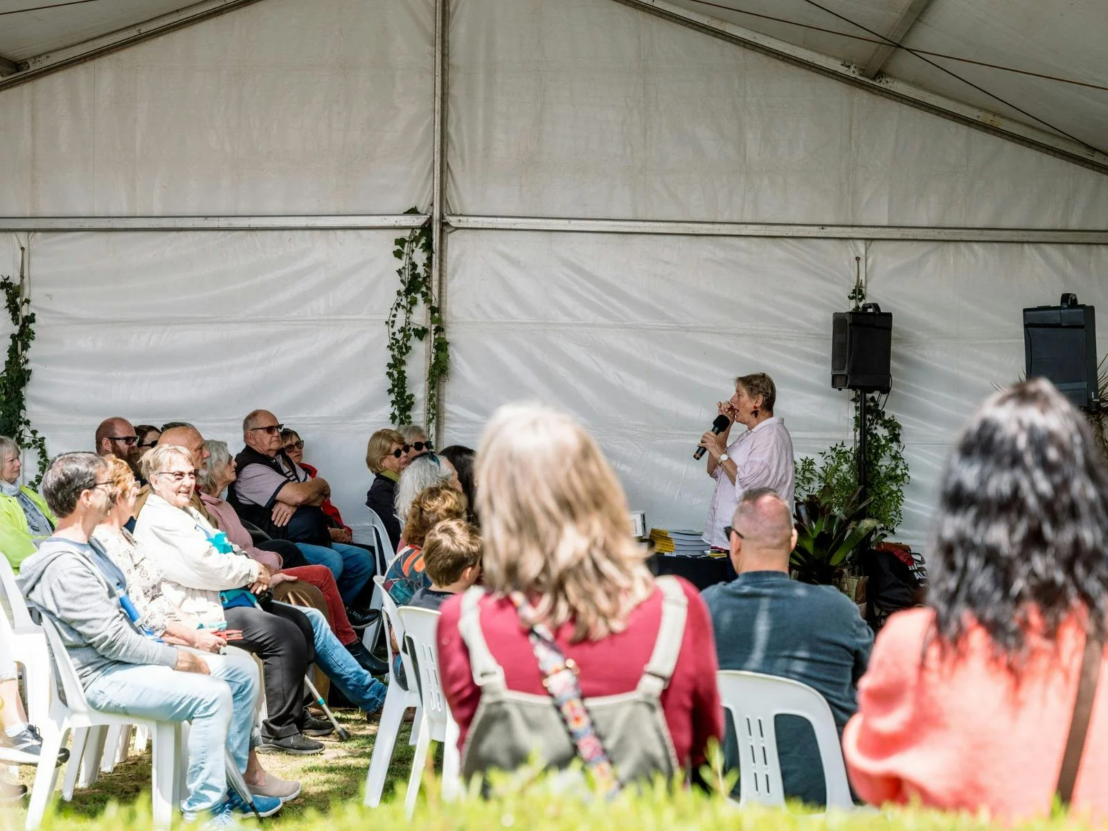 Wide image of a guest speaker in a marquee presenting to a group of patrons