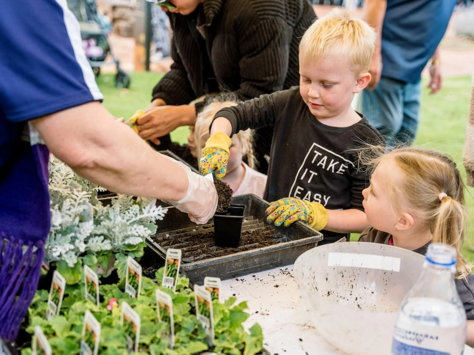 Close up of a child being assisted with adding potting mix to their pot