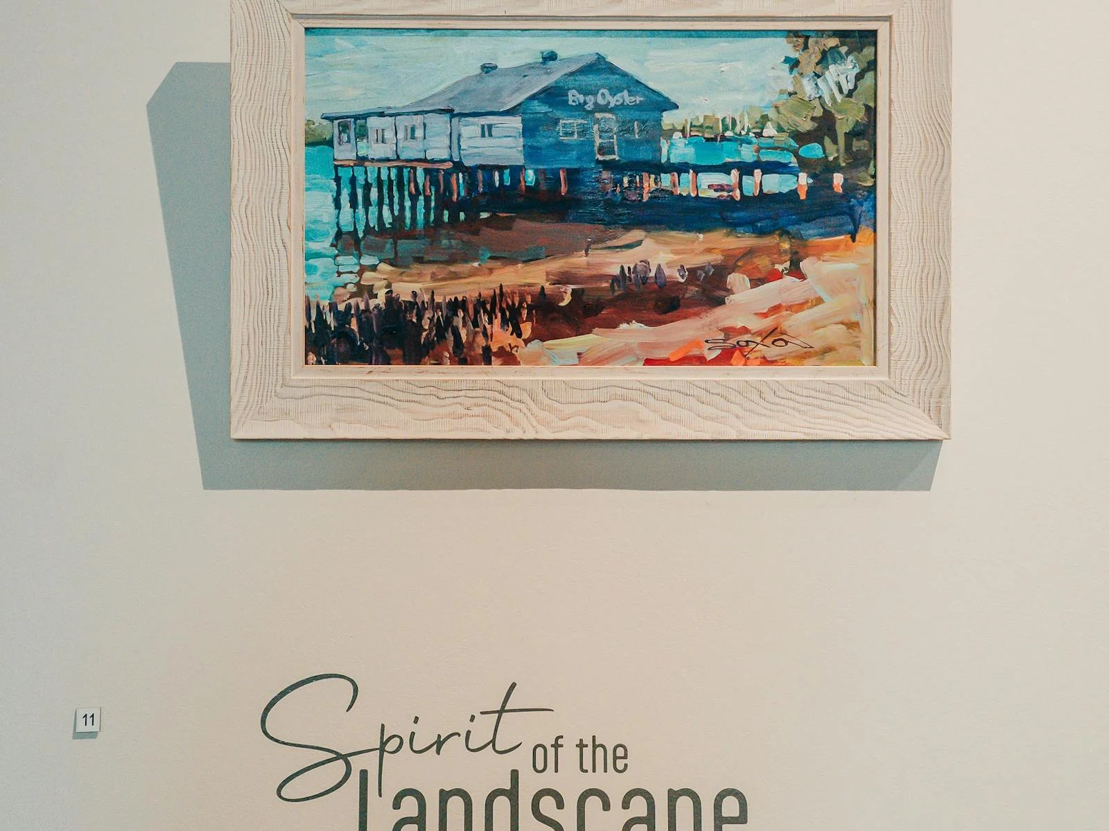 Painting of a boat house an water hanging in a gallery in Mandurah