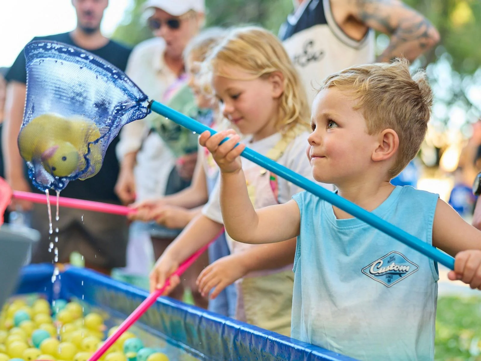 young boy lifting a toy duck in a net from a duck-fishing game