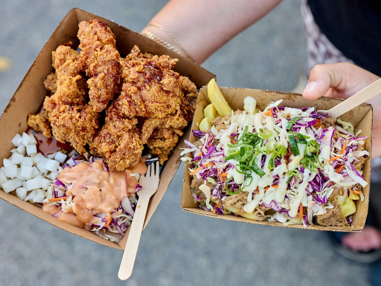Hands holding two take-away boxes of food-truck food